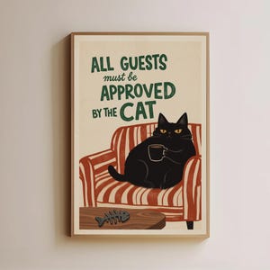 Puede incluir: Un cartel enmarcado con el texto "ALL GUESTS must be APPROVED BY THE CAT". Un gato negro con ojos amarillos está sentado en un sillón a rayas rojas y blancas, sosteniendo una taza de café. Una pequeña mesa de madera con una ilustración de espina de pescado está delante.