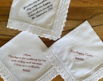 May include: Three white square handkerchiefs with scalloped lace edges. One features black embroidered text: You are my sunshine, My only sunshine, You make me happy, When skies are grey, 5th September 2026. Others have brown text: Mum, Thankyou for walking by my side today and always, I love you endlessly, 22.04.27 and For Happy Tears, 09.05.2026.