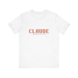May include: White t-shirt with the name "CLAUDE" in a brick-like font. Below the name is the text "--dangerouslySkipPermissions" in a smaller font. The shirt is made of a soft material.