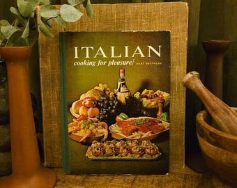 Może przedstawiać: Książka kucharska w twardej oprawie zatytułowana Italian Cooking for Pleasure autorstwa Mary Reynolds. Okładka przedstawia fotografię martwej natury z różnymi włoskimi potrawami, w tym makaronem, owocami morza, świeżymi owocami i butelką wina.