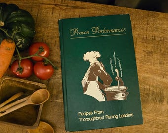 Może przedstawiać: Ciemnozielona książka kucharska w twardej oprawie zatytułowana Proven Performances: Recipes From Thoroughbred Racing Leaders, z grafiką konia w czapce kucharskiej i fartuchu mieszającego w garnku, w otoczeniu świeżych produktów i drewnianych łyżek.
