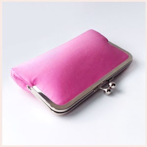 May include: A pink satin clutch purse with a silver metal frame and clasp.