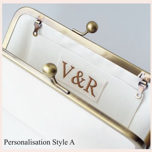 example of personalised monogram embroidered in bronze thread on ivory silk label sewn onto interior pocket of wedding clutch bag with antique brass tone kisslock frame