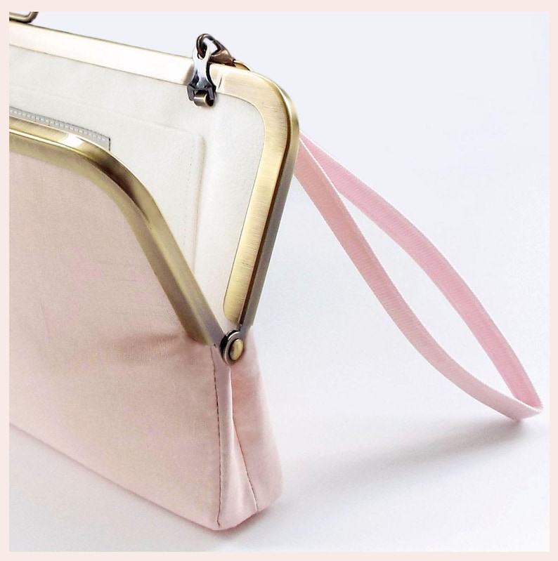 detail of pale pink wedding clutch bag with Antique Brass tone kisslock frame and pink wristlet has white lining