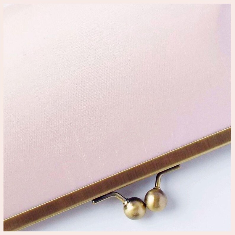detail of pale pink wedding clutch bag with Antique Brass tone frame has kisslock clasp