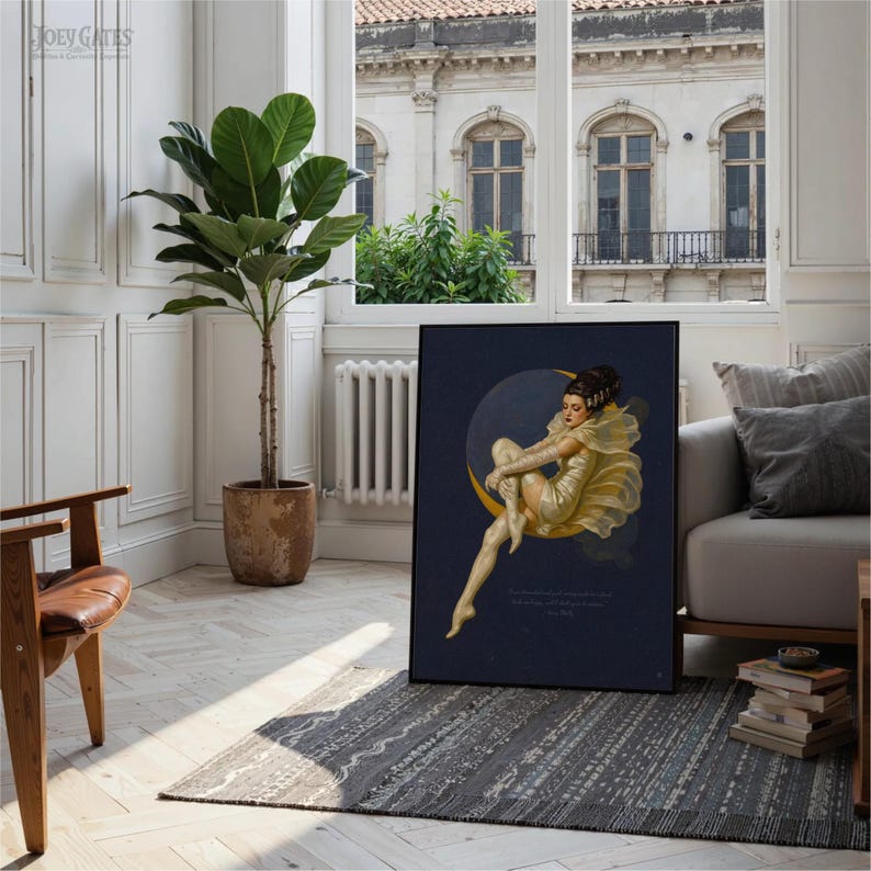 Puede incluir: Impresi&oacute;n art&iacute;stica enmarcada que representa a una mujer sentada en una luna creciente. La obra de arte tiene un fondo azul oscuro con tonos dorados y amarillos. La impresi&oacute;n se exhibe en una habitaci&oacute;n con una gran planta en maceta y una ventana.