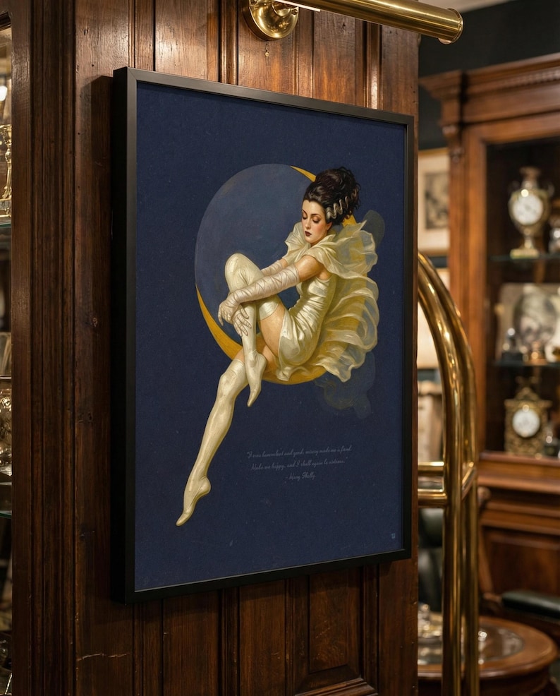 Puede incluir: Impresi&oacute;n art&iacute;stica enmarcada que representa a una mujer con un vestido amarillo sentada en una luna creciente sobre un fondo azul oscuro. La obra de arte tiene un estilo vintage, con una cita en la parte inferior. El marco es negro y la impresi&oacute;n est&aacute; montada en una pared de madera.