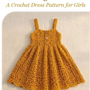 May include: Golden marigold sundress, a crochet dress pattern for girls. The dress is a vibrant golden yellow, featuring a detailed crochet design. It has a fitted bodice with button closures and a flared skirt. The straps are also crocheted.