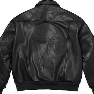 K&ouml;nnte beinhalten: Eine schwarze Lederjacke mit einem gro&szlig;en gepr&auml;gten Spinnenemblem auf dem R&uuml;ckenteil. Die Schultern und &Auml;rmel sind mit einem gesteppten Spinnennetz-Muster versehen. Die Jacke verf&uuml;gt &uuml;ber einen klassischen Kragen sowie gerippte B&uuml;ndchen.