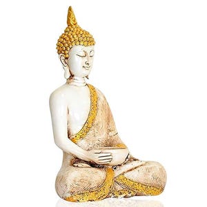 Op de afbeelding: Een serene Boeddha-beeld in een zittende meditatiehouding. De figuur is voornamelijk wit met gouden accenten op het hoofd, de rand van de mantel en de basis. Het beeld houdt een kleine kom vast en heeft gesloten ogen, wat duidt op vrede en contemplatie.
