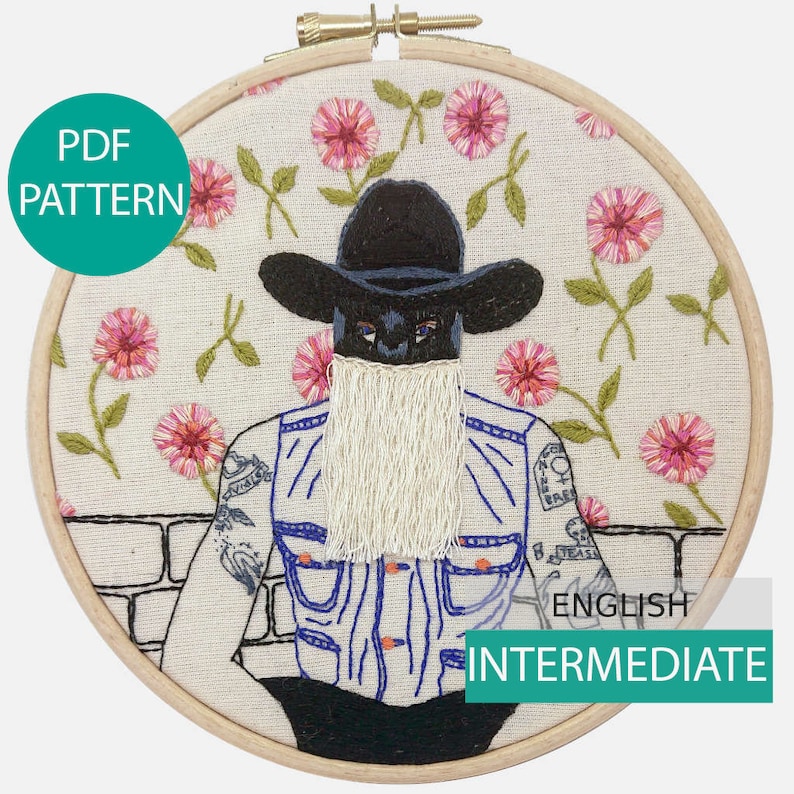 K&ouml;nnte beinhalten: Stickbild mit Stickerei, das einen schwarz-wei&szlig;en Cowboy mit langem wei&szlig;em Bart zeigt, der eine Jeansweste und einen schwarzen Cowboyhut tr&auml;gt. Der Hintergrund ist ein wei&szlig;er Stoff mit rosa Blumen.