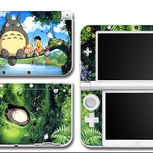 May include: Nintendo 3DS console skins featuring artwork from the animated film, 'My Neighbor Totoro.' Designs include scenes with Totoro and forest imagery. The consoles are white with colorful graphics.