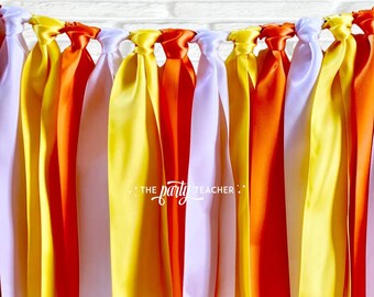 May include: A candy corn themed party banner with white, orange, and yellow satin ribbon streamers tied together. The banner says "THE party TEACHER".