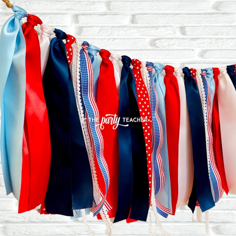 May include: Red, white, and blue ribbon banner with a white background. The banner is made of various ribbons with different patterns, including polka dots, stripes, and lace.