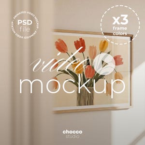 May include: A rectangular wall frame containing a print of a bouquet of red, orange, and yellow tulips in a striped vase. The frame is light wood. Text overlays include PSD file, animated video mockup, x3 frame colours, and video mockup.