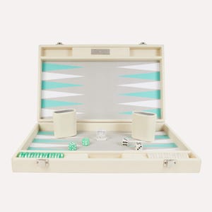 Puede incluir: Juego de backgammon marfil abierto con una superficie de juego gris y turquesa. Incluye cubiletes de dados marfil, dados y fichas. El juego tiene un diseño clásico y elegante.