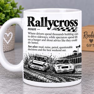 May include: A white ceramic mug featuring a black graphic print of two rally cars racing on a dirt track. The text reads Rallycross noun, followed by a humorous definition about drivers and spectators, and a see also section with listed terms.