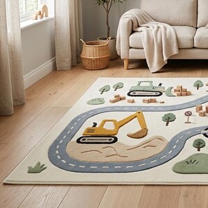 May include: A rectangular area rug featuring a cream-colored background with a construction-themed design. The rug displays a gray winding road, a yellow excavator, a green bulldozer, small green trees, and brown mounds of dirt.