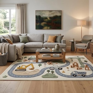 May include: A rectangular area rug featuring a light cream background with a winding gray road pattern, illustrated construction vehicles including a yellow excavator and a gray dump truck, green hills, and small wooden block structures.