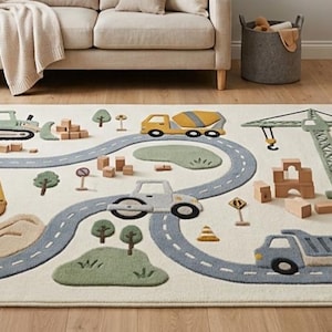 May include: A rectangular area rug featuring a construction site theme with a winding gray road, a yellow cement mixer, a green bulldozer, a gray steamroller, a blue dump truck, a green crane, small trees, traffic signs, and wooden blocks.