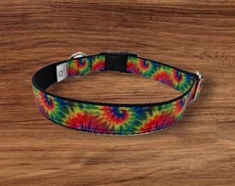 May include: A tie-dye dog collar with a black nylon strap and a silver metal buckle. The collar has a colorful tie-dye pattern with swirls of red, yellow, blue, and green.