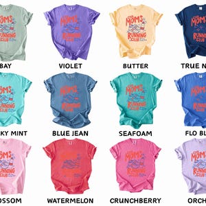 K&ouml;nnte beinhalten: Zw&ouml;lf T-Shirts in verschiedenen Farben, jeweils mit dem Aufdruck "Cool Moms Running Club" und einer Grafik von Laufschuhen und einer Wasserflasche. Farben: Bay, Violett, Butter und Marineblau.