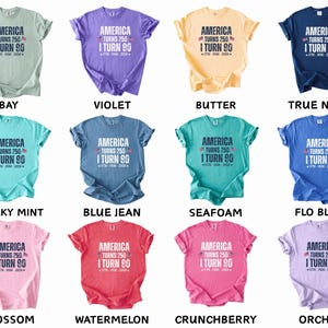 May include: A collection of twelve short-sleeved t-shirts in various colors, each featuring the text "AMERICA TURNS 250 I TURN 90" in a bold, patriotic design. The shirts are available in shades like bay, violet, butter, and true navy.