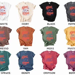 K&ouml;nnte beinhalten: Eine Auswahl an T-Shirts in verschiedenen Farben, jeweils mit dem Text "Cool Moms Running Club" in Rot und Blau. Das Design umfasst einen Laufschuh und eine Wasserflasche. Farben sind unter anderem Wei&szlig;, Schwarz und Senf.