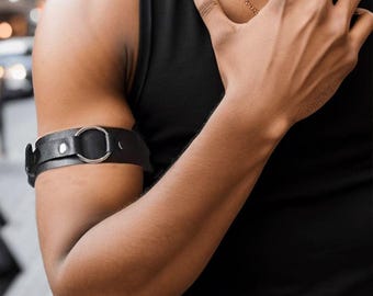 Brazalete de cuero negro con anilla, puño ajustable para bíceps estilo punk, accesorio de estilo urbano.