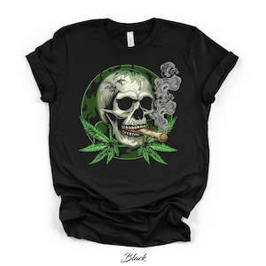 Könnte beinhalten: Schwarzes T-Shirt mit einem rauchenden Totenkopf, umgeben von grünen Cannabisblättern und einem grünen Kreis. Das Wort "Black" ist unten auf dem T-Shirt aufgedruckt.