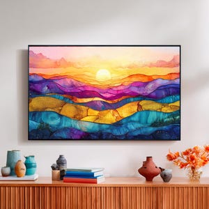 May include: Abstract landscape art print featuring a vibrant sunset over rolling hills. The artwork uses a palette of purple, gold, blue, and orange hues. The framed print is displayed above a wooden cabinet with decorative items.
