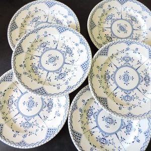 Peut inclure: Un ensemble de six assiettes en céramique blanche avec un motif floral bleu. Chaque assiette présente un médaillon central et une bordure décorative. Les assiettes sont disposées en cercle, mettant en valeur leurs détails et leur style classique.