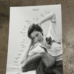以下が含まれることがあります： 短い髪の人物が花柄のアクセントが付いた半袖シャツを着ている白黒のポスター。ポスターには「Daughter from Hell (Gracie Abrams)」というテキストと、1から16までの曲名と時間が記載されたトラックリストが含まれています。