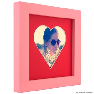 May include: A pink picture frame with a heart-shaped cutout. The frame is made of wood and has a red mat. The heart-shaped cutout is in the center of the mat. *Picture not included*