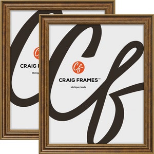 May include: Two gold picture frames with a beveled edge and a decorative beading detail. The frames are made in Michigan and feature the Craig Frames logo.