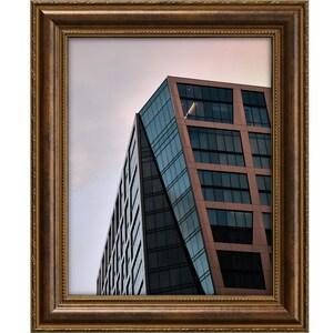 Pu&ograve; includere: Un moderno edificio per uffici con una facciata in vetro e rame contro un cielo nuvoloso.