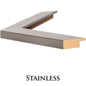 May include: A close-up of a corner of a silver picture frame with a wood backing. The frame has a brushed metal finish. The text "STAINLESS" is printed below the frame.
