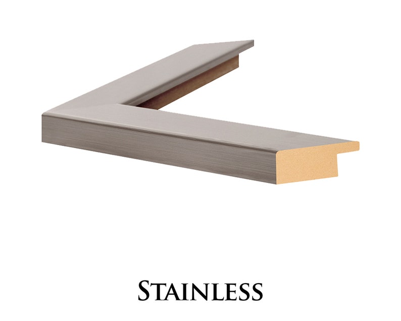May include: A close-up of a corner of a silver picture frame with a wood backing. The frame has a brushed metal finish. The text "STAINLESS" is printed below the frame.
