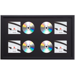 May include: Black framed CD display case with four CDs and four square spaces for artwork. The CDs have a reflective, rainbow-like surface. The square spaces have the text "CRAIS FRAMES" and "hangs vertical or horizontal".