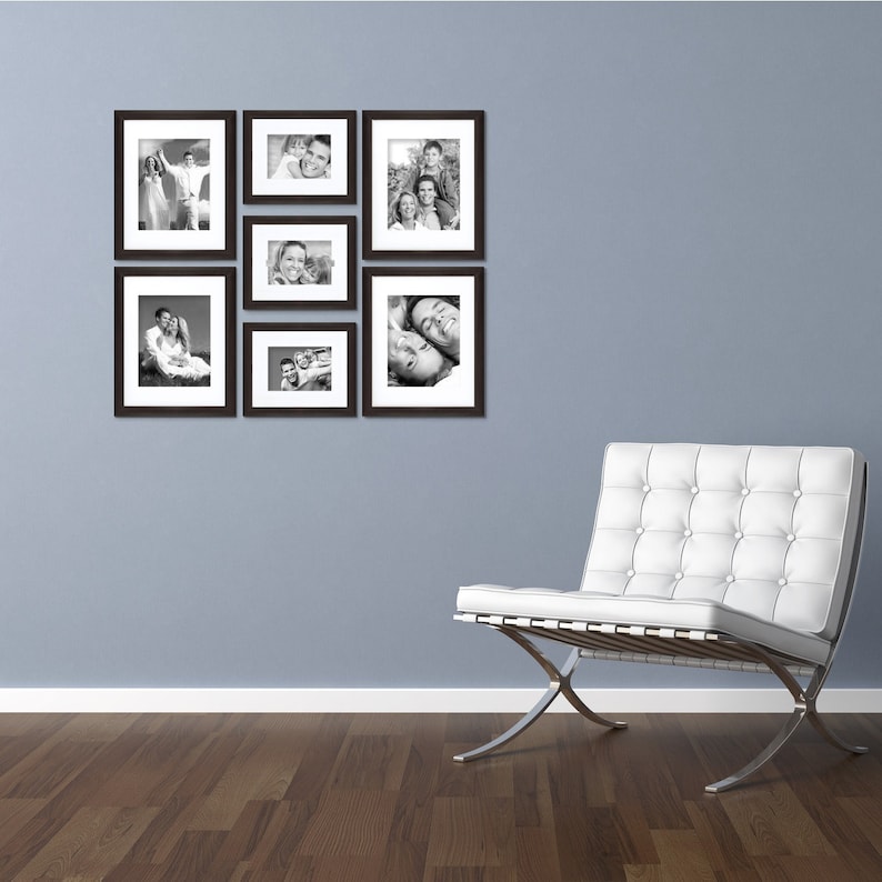 May include: A white leather armchair with a tufted back and a chrome frame sits in front of a wall with a gallery of black and white framed photos.