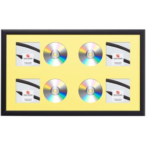 May include: Black picture frame with a yellow mat and six openings for displaying CDs or DVDs. The frame has a label that reads "Craig Frames hangs vertical or horizontal".