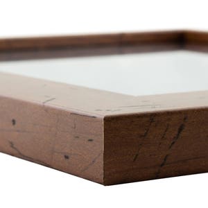 May include: A brown wooden picture frame with a distressed finish. The frame has a simple, rectangular shape and a smooth surface.