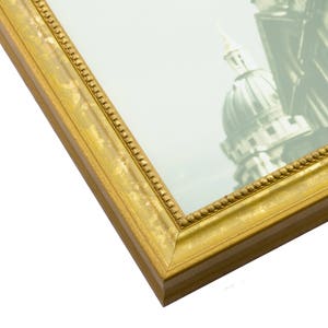 May include: A gold picture frame with a decorative border. The frame is made of wood and has a matte finish.