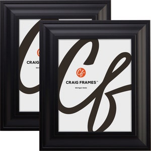 May include: Two black picture frames with a simple, classic design. The frames are made in Michigan and feature the Craig Frames logo.