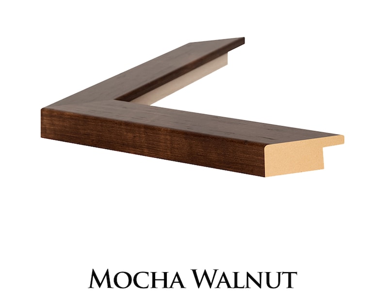 May include: Close-up of a dark brown wood picture frame with a slightly raised edge. The frame has a smooth finish and a subtle wood grain pattern. The frame is labelled "MOCHA WALNUT".