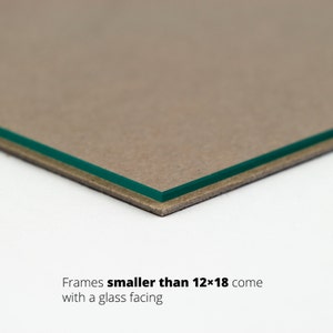 May include: Close-up of the edge of a picture frame showing a brown cardboard backing and a green glass facing. Text reads "Frames smaller than 12x18 come with a glass facing."