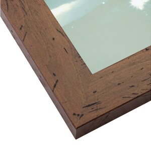 May include: Close-up of a brown wood picture frame with a distressed finish. The frame has a beveled edge and a smooth surface.