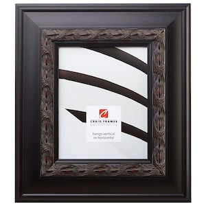 May include: A black picture frame with an ornate, carved, brown wood design. The frame has a red accent along the inner edge. The frame hangs vertically or horizontally. "Craig Frames" and "www.craigframes.com" are printed on the mat.