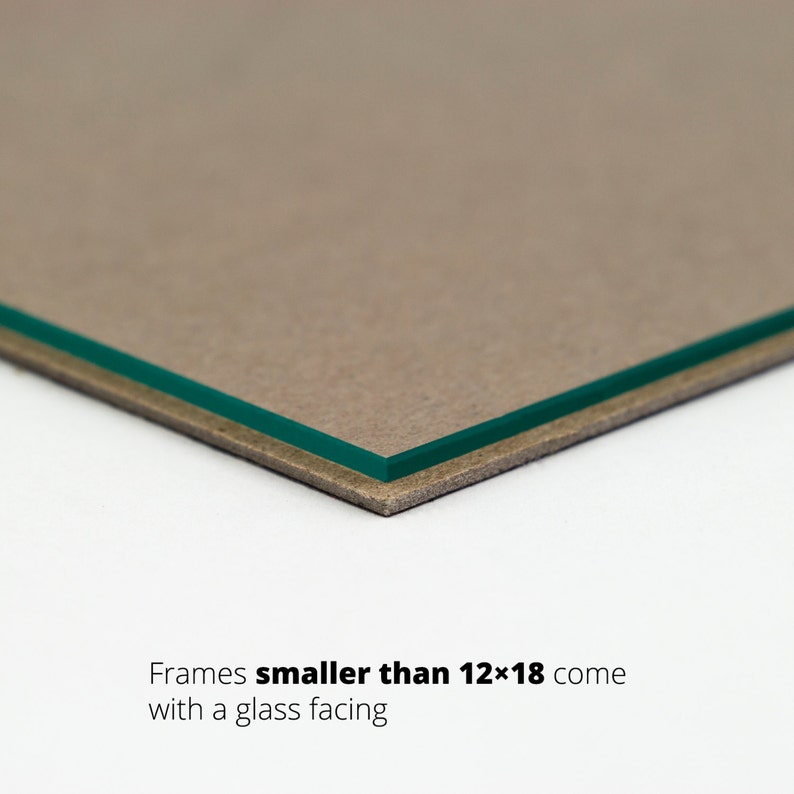 May include: Close-up of the edge of a picture frame showing a brown cardboard backing and a green glass facing. Text reads "Frames smaller than 12x18 come with a glass facing."