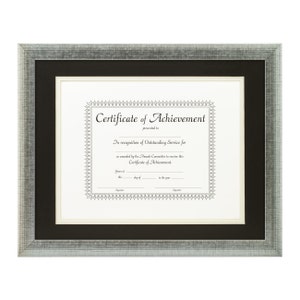 May include: A silver framed certificate of achievement with a black mat. The certificate is printed on cream paper and has a decorative border. The text reads "Certificate of Achievement" and "In recognition of Outstanding Service for".